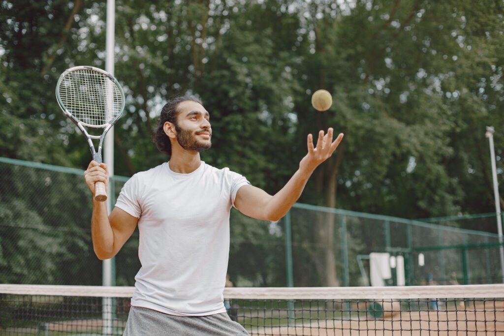 Indian male tennis player playing on the court outdoors